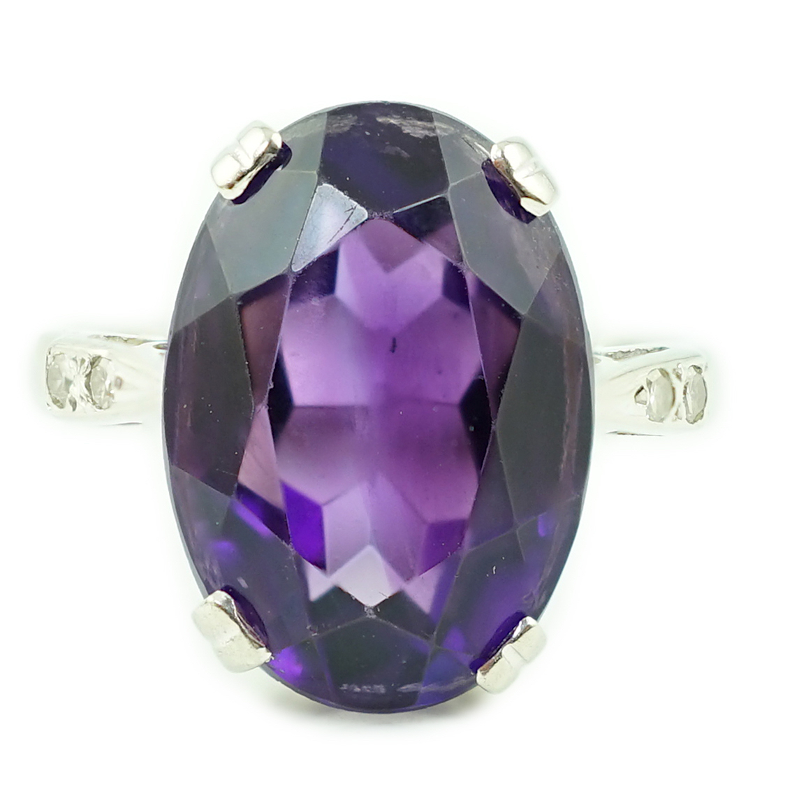 An 18ct white gold and oval cut amethyst set ring, with two stone diamond chip set shoulders